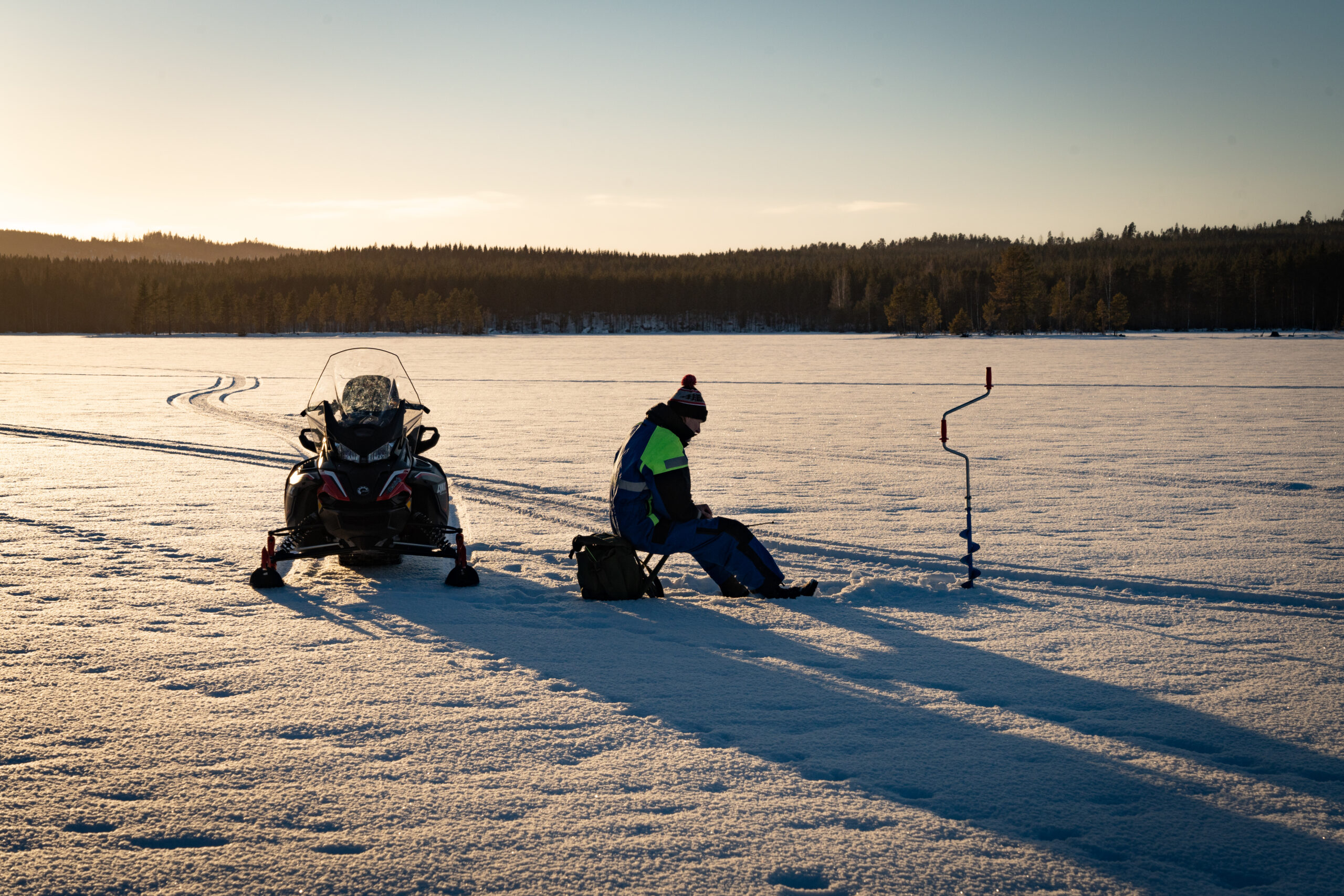 Ijsvissen op het bevroren meer in Zweden. Samen met een sneeuwscooter
