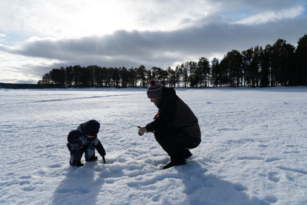 Vader en zoon samen aan het ijsvissen op het bevroren meer in Zweden
