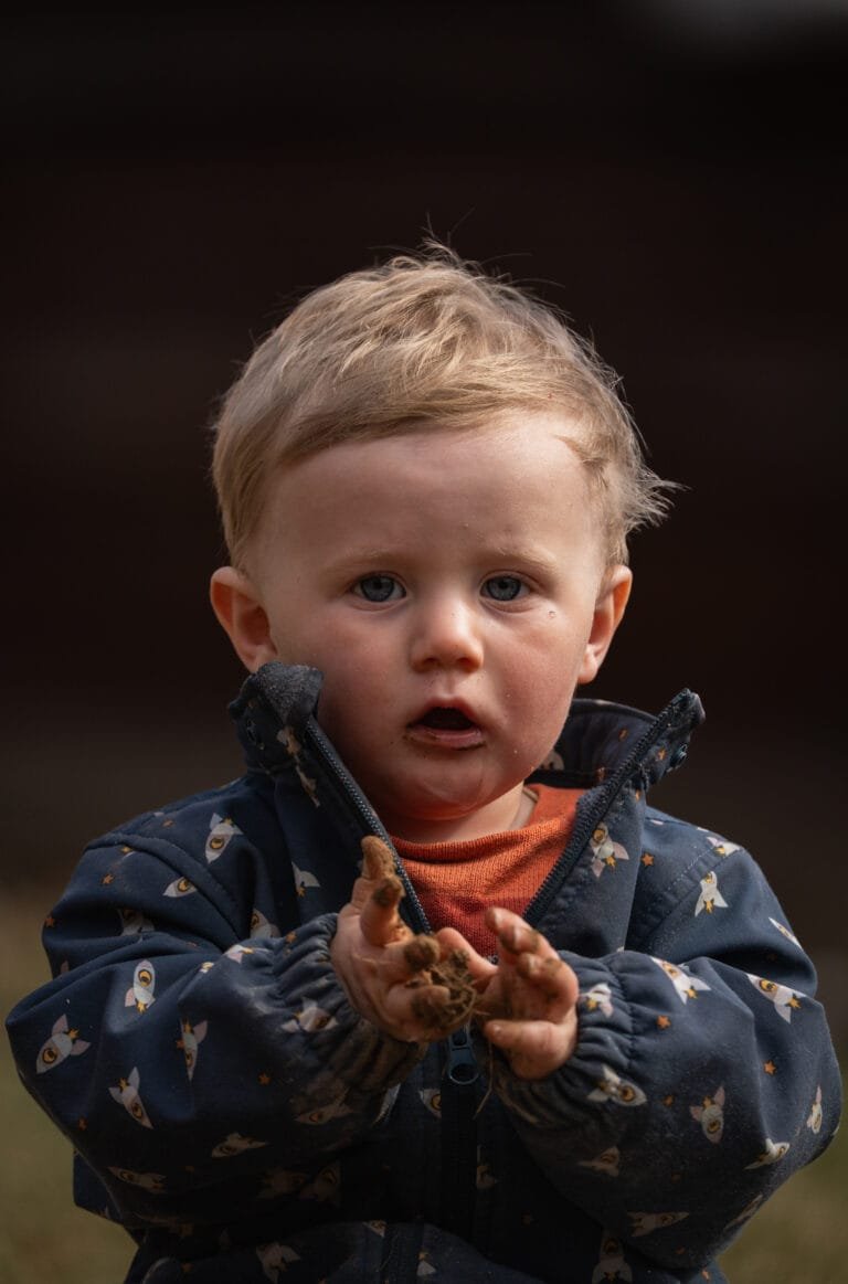 Een jongen van 1 jaar aan het experimenteren en buitenspelen met zand