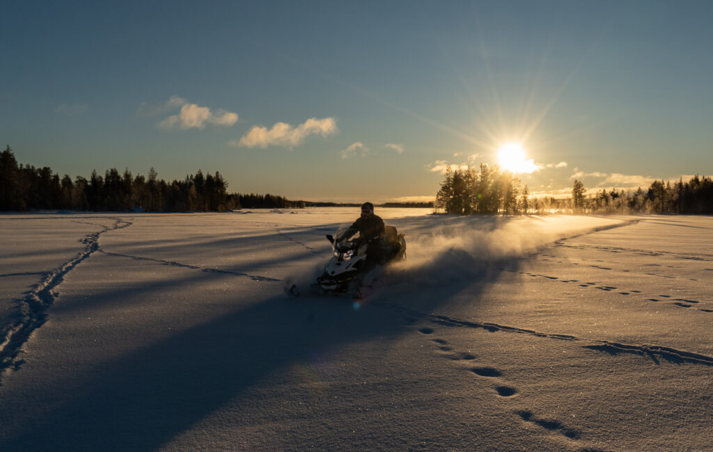 Met de sneeuwscooter over het meer in Zweden met opkomende zon