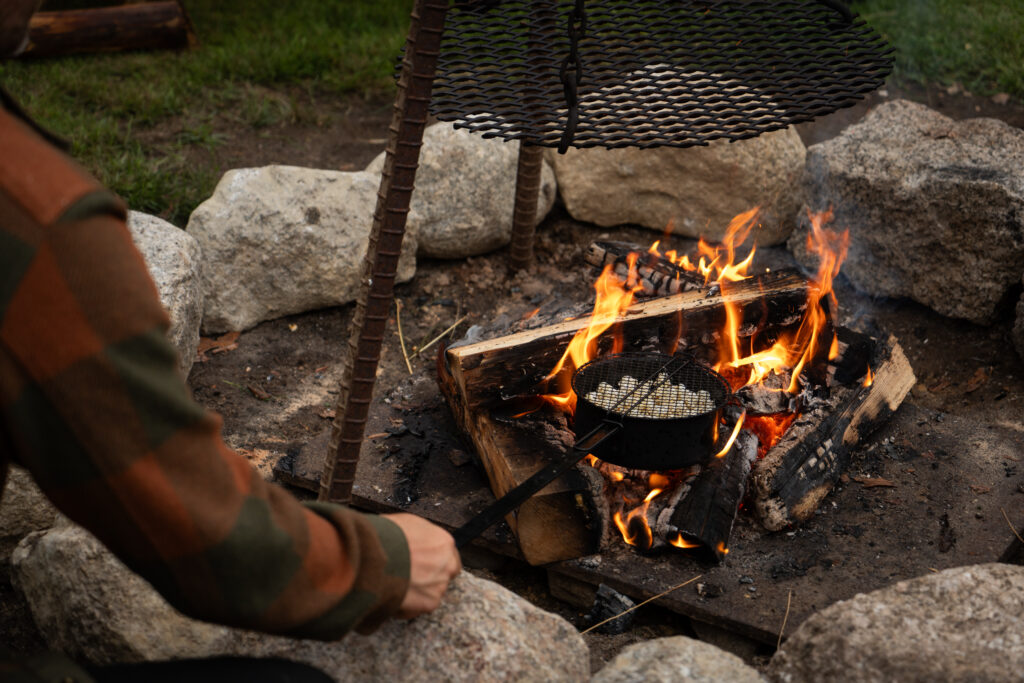 Popcorn maken in een speciale pan op het vuur bij de vuurplaats van Friluft Sweden