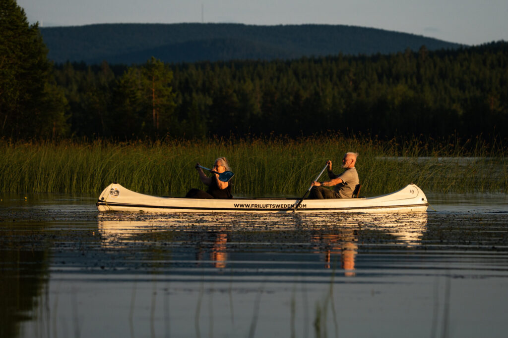 Twee mensen aan het kanoën op het meer in Zweden bij Friluft Sweden. Bergen op de achtergrond.