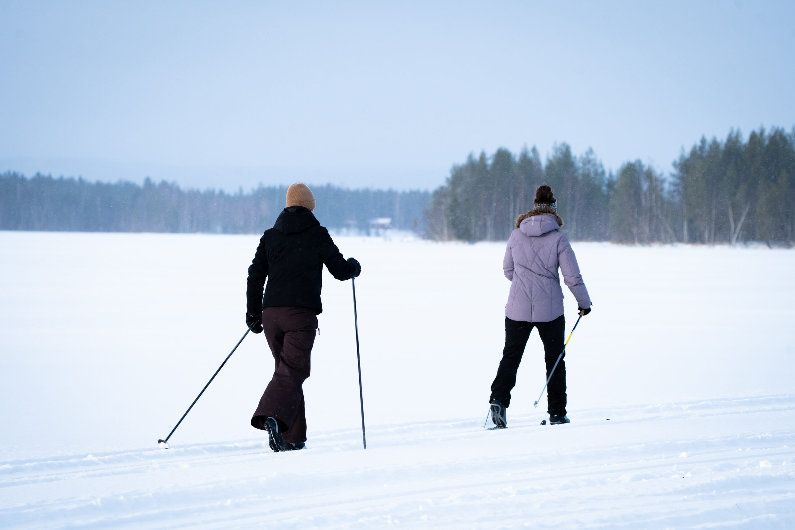 Twee vrouwen langlaufen over het bevroren meer in Zweden bij Friluft Sweden