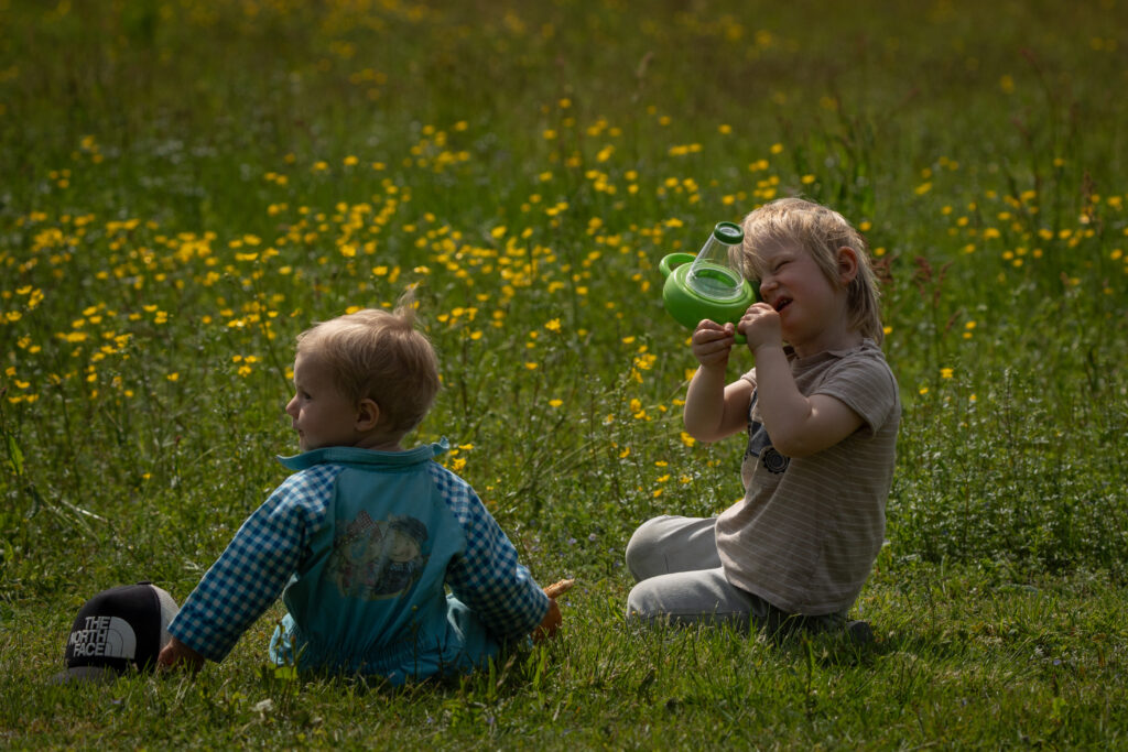 Twee kinderen in de maand juni in Zweden. Ze kijken naar insecten in de natuur omgeven door bloemen bij Friluft Sweden