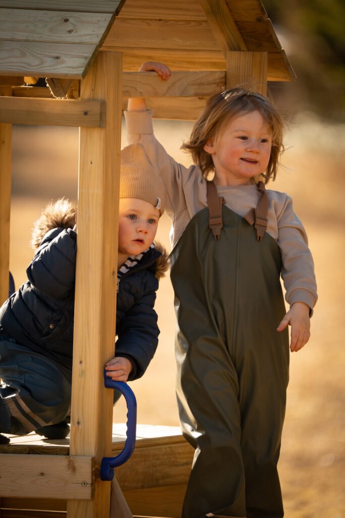 Twee kinderen buiten aan het spelen in de natuur in de herfst in Zweden bij Friluft Sweden