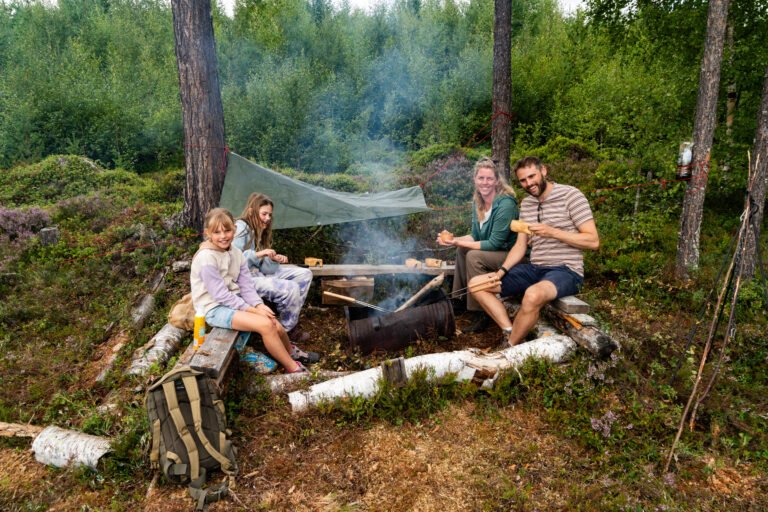 Een gezin in de natuur met een vuurtje in Zweden op gezinsvakantie bij Friluft Sweden